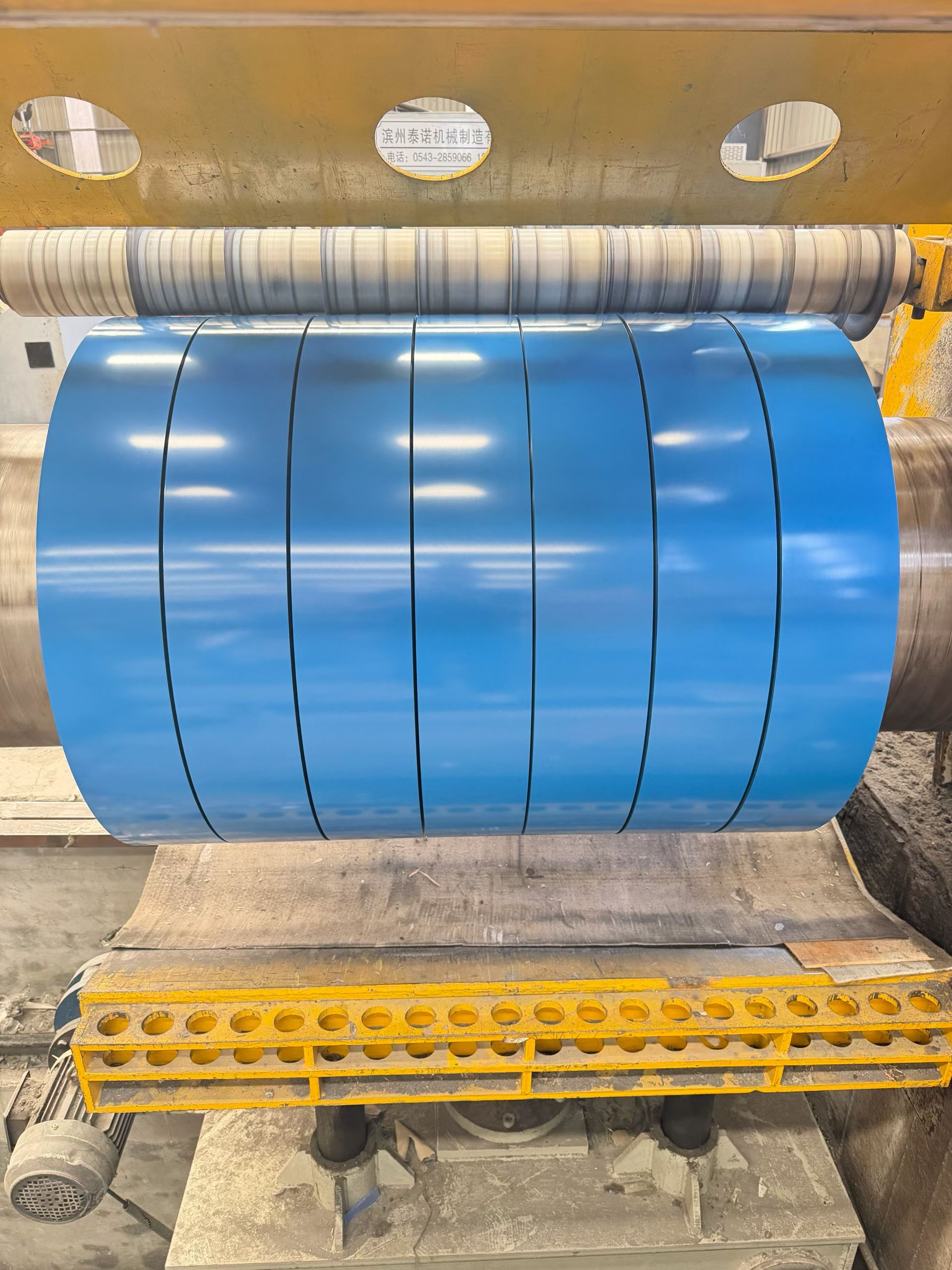 Blue coated steel being slit into narrower coils